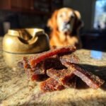 A pile of Beef Quinoa Power Jerky on a granite countertop with a golden retriever in the background.