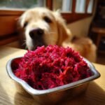 A metal bowl filled with shredded beetroot, with a golden retriever dog looking intently in the background. This is part of a Chicken and Beetroot Skin Health Mix recipe.
