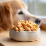 A bowl filled with Homemade Chicken and Carrot Mini Crisp Kibbles, with a golden retriever looking on in the background.