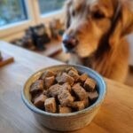 A bowl filled with Homemade Turkey and Spinach Lean Muscle Kibble, with a golden retriever waiting eagerly in the background.