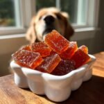 Close-up of Homemade Vet Approved Bone Broth Gummies in a white bowl, with a curious dog in the background.