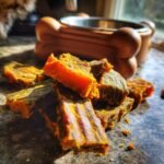 A pile of homemade Lamb and Pumpkin Fitness Jerky pieces, showing their textured, dried appearance.