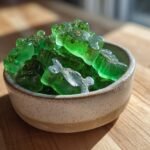 Close-up of bright green, bear-shaped Mint & Parsley Bone Broth Dental Gummies in a speckled ceramic bowl.