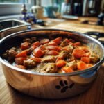 A close-up of Turkey and Carrot Golden Wellness Stew in a metal pot with a paw print design.