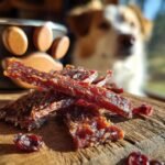 A pile of Turkey Cranberry Holiday Jerky on a wooden surface, with a dog in the blurred background.