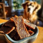 A bowl overflowing with homemade Turkey Pumpkin Lean Jerky, with a golden retriever dog in the blurred background.